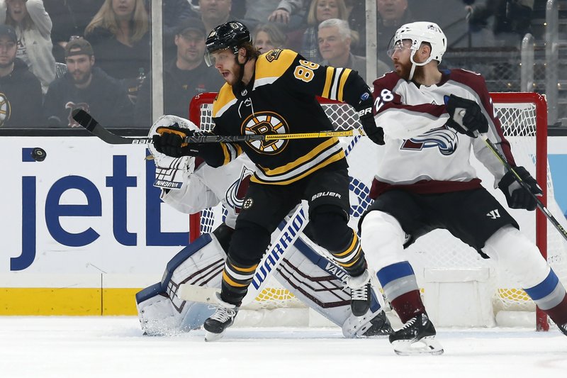 Boston Bruins' David Pastrnak (88) tries to deflect a shot past Colorado Avalanche goalie Pavel Francouz, behind, as Ian Cole (28) defends during the third period of Saturday's game in Boston. - Photo by Michael Dwyer of The Associated Press