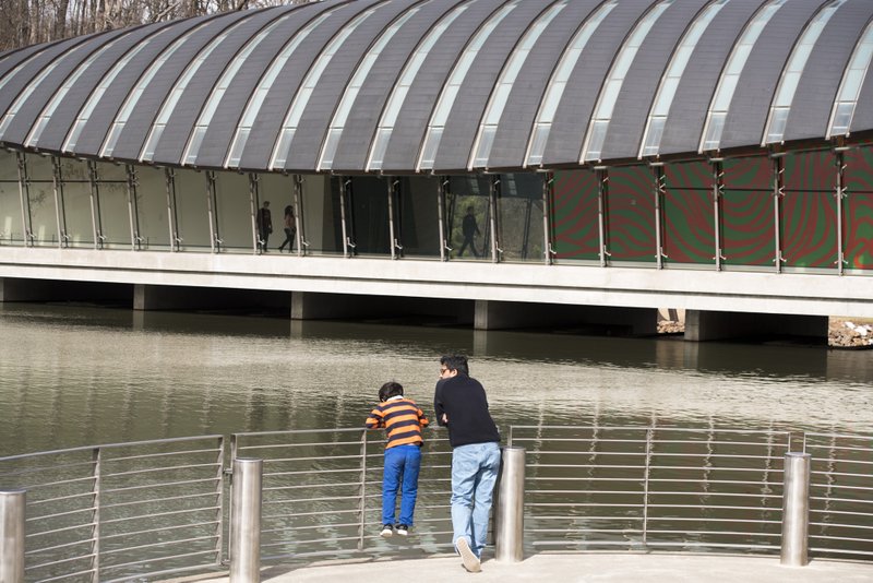 In this 2018 file photo, Chakra Dusetti of Bentonville looks out onto the water with his son at Crystal Bridges in Bentonville.