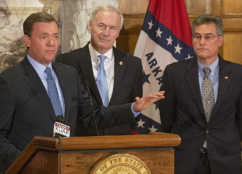 Gov. Asa Hutchinson, center, and Rep Charlie Collins, R-Fayetteville, right, listen to comments from NRA Institute for Legislative Action executive director Chris Cox, left, about the benifits of HB 1249 which Hutchinson signed into law Wednesday. The bill expands the places concealed-carry permit holders can take their guns in Arkansas. 