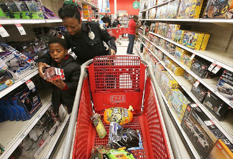 Little Rock police officer Nikie Musaddiq looks for toys Saturday with Roderick Benson, 7, during the Heroes and Helpers event at the Target store on Chenal Parkway in Little Rock. More photos are available at www.arkansasonline.com/1215heroes/. 