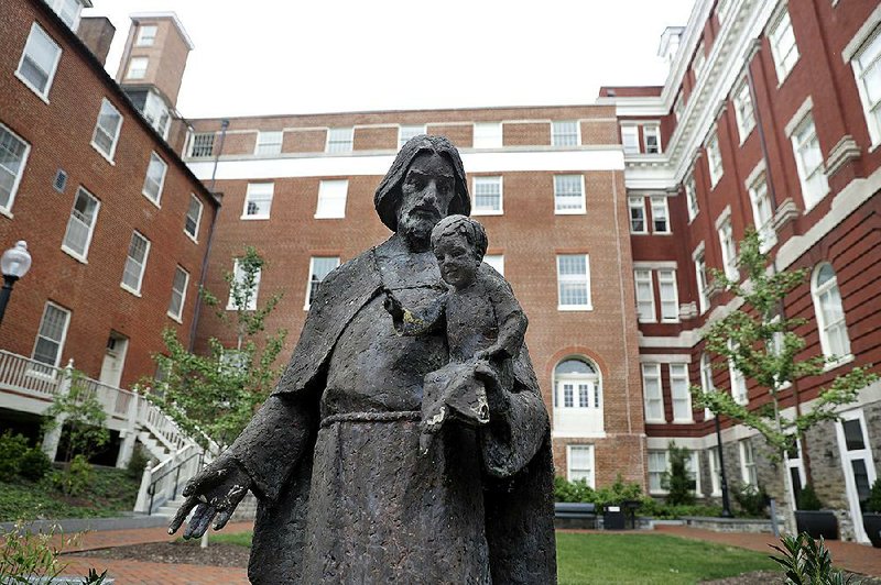 A Jesuit statue sits in front of Georgetown University’s Freedom Hall, formerly Mulledy Hall, which was named for a Georgetown president involved in the sale of slaves in the 1800s. Now the school and two seminaries are funding commitments to aid descendants of those who were sold or who labored to benefit the institutions. 