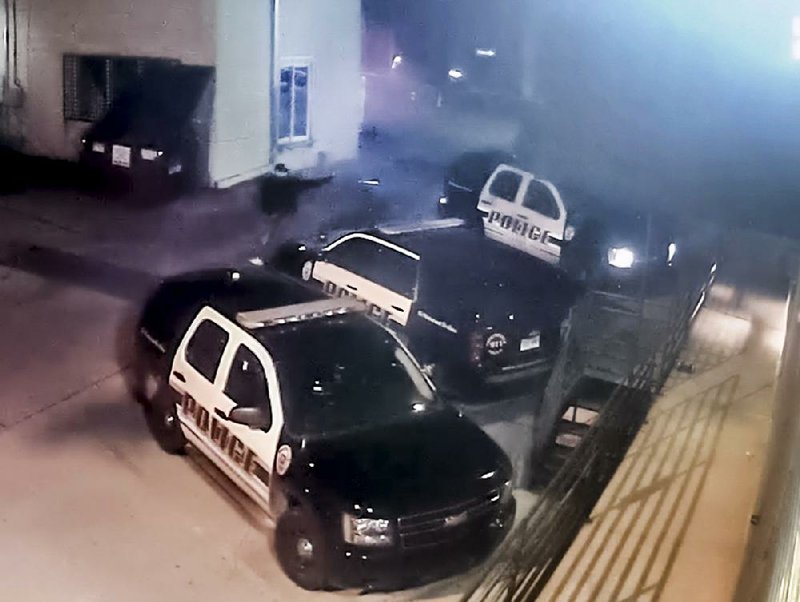 An image taken from video shows the muzzle flash as a man fires a handgun while walking through a Fayetteville Police Department parking lot Dec. 7. Officer Stephen Carr was killed when a gunman fired several rounds while Carr sat in his patrol vehicle. 