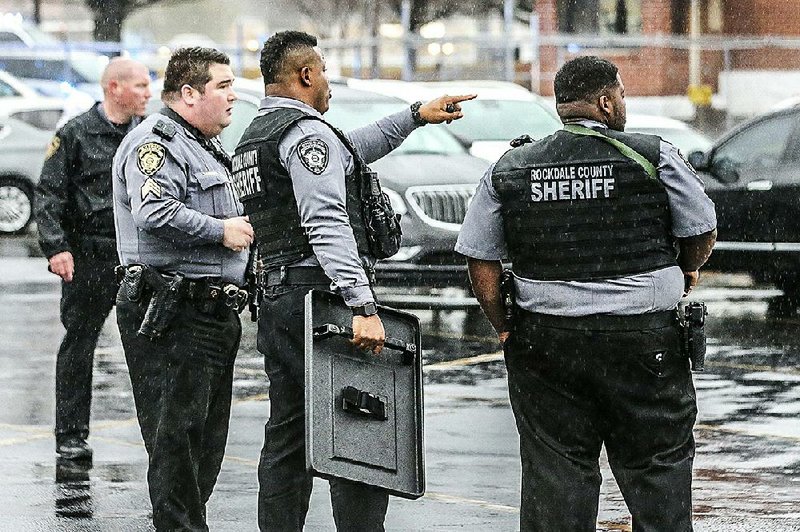 Authorities stand outside the Dart Container facility in Conyers, Ga., where a worker was killed Friday in an early morning shooting.  