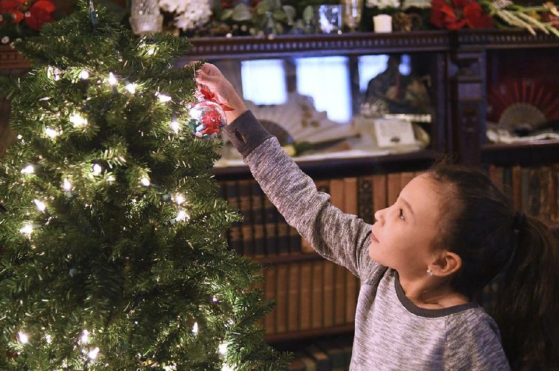 Halle Koenig, 8, places an ornament on a Christmas tree during a workshop Sunday at Ventfort Hall in Lenox, Mass. Halle had crafted the ornament with her family.  