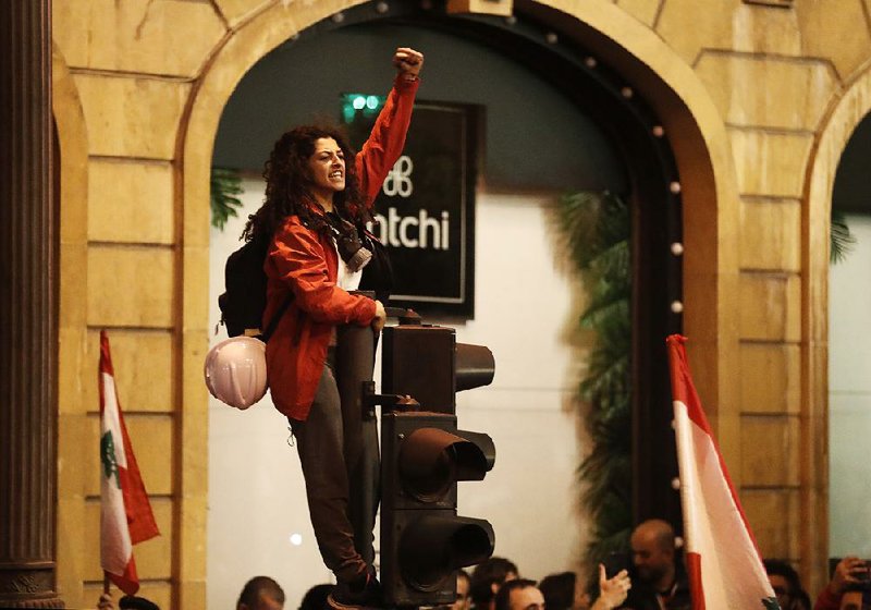 An anti-government protester stands on a traffic light Sunday as she shouts slogans during a demonstration in Beirut. More photos at arkansasonline.com/1216lebanon/.  