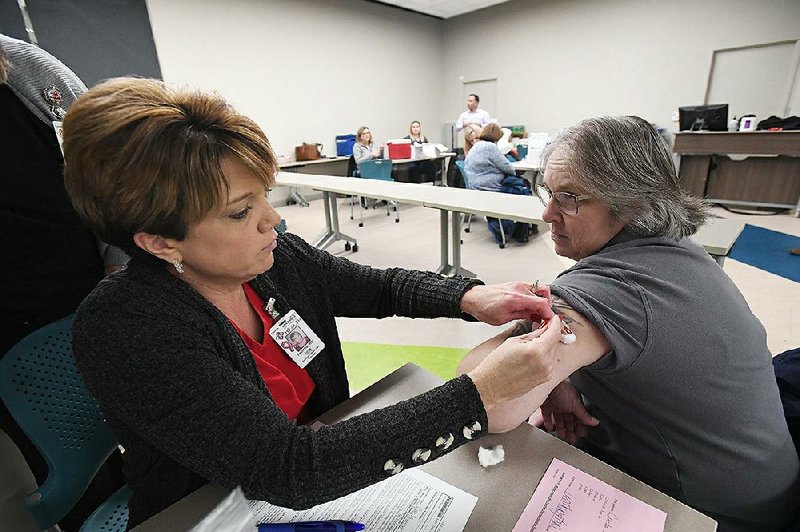 Tabitha Gibbs, a registered nurse with the Arkansas Department of Health, puts a bandage on Carla Foster after giving her a vaccination Monday in the Pat Walker Health Center at the University of Arkansas, Fayetteville. 