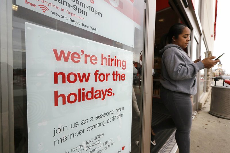 In this Nov. 27, 2019 photo a passer-by walks past a hiring for the holidays sign near an entrance to a Target store location, in Westwood, Mass. On Wednesday, Dec. 4, payroll processor ADP reports on how many jobs its survey estimates U.S. companies added in November. (AP Photo/Steven Senne)