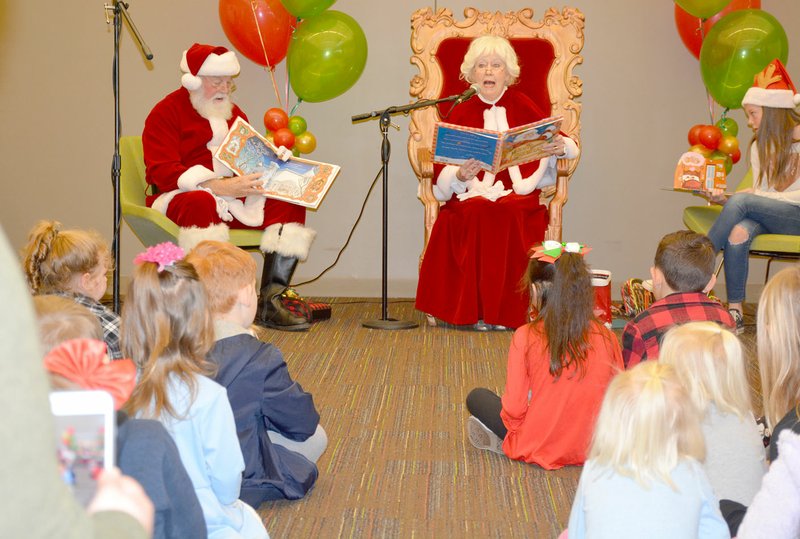 Graham Thomas/Herald-Leader Children of all ages look on as Mrs. Claus reads &quot;The Night Before Christmas&quot; and Santa Claus shows pictures Saturday at the Siloam Springs Public Library.