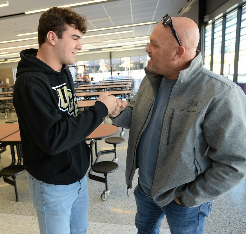 NWA Democrat-Gazette/ANDY SHUPE Fayetteville senior Quade Mosier (left) is congratulated Wednesday, Dec. 18, 2019, by former Fayetteville football coach Billy Dawson before Mosier signed a letter of intent to play football for Central Florida during a ceremony at the school. Go to http://bit.ly/35GXaH2 to check out a gallery from the event.