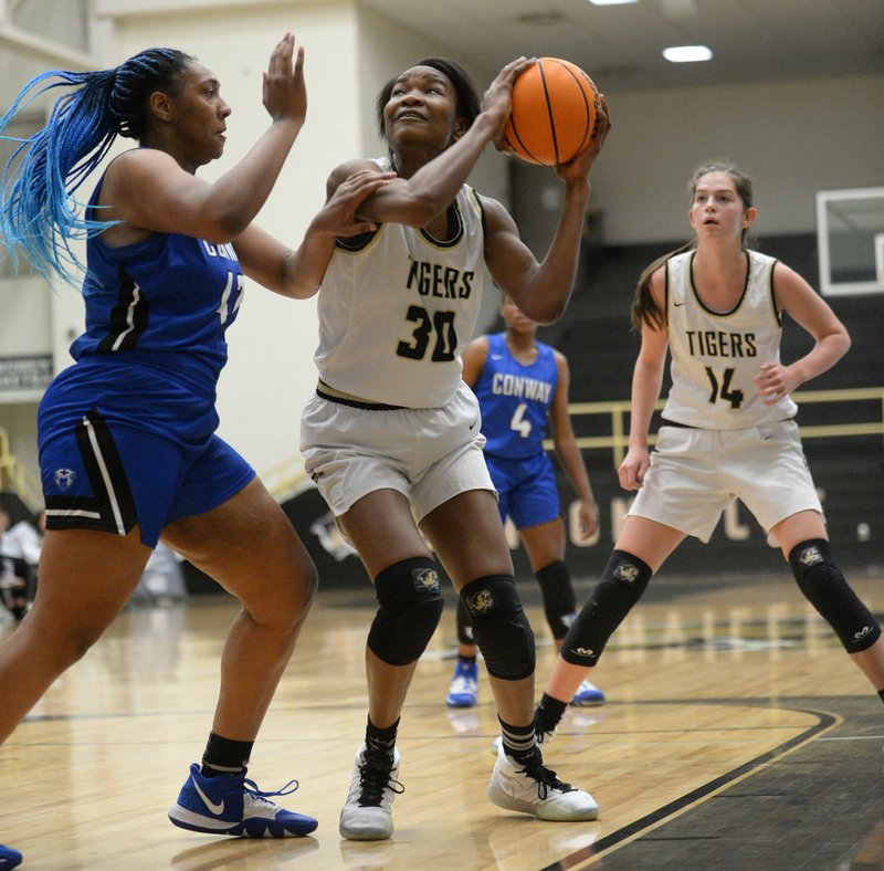 NWA Democrat-Gazette/ANDY SHUPE Bentonville's Maryam Dauda (30) takes a shot in the lane Friday, Dec. 20, 2019, as Conway's Savannah Scott (left) defends during the first half of play of the Malik Monk Classic in Tiger Arena in Bentonville. Visit http://bit.ly/2Mvuucv to see more photographs from the game.