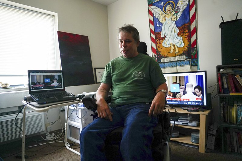 Darrell Price sits in his power wheelchair in his apartment in Cleveland In this July 2017 file photo. Price relies on a Medicaid-funded assistant to help him get dressed, washed and fed. In Arkansas, such assistants are having their work hours reduced because state budgeting has not accounted for the increase in the minimum wage taking effect on Jan. 1.