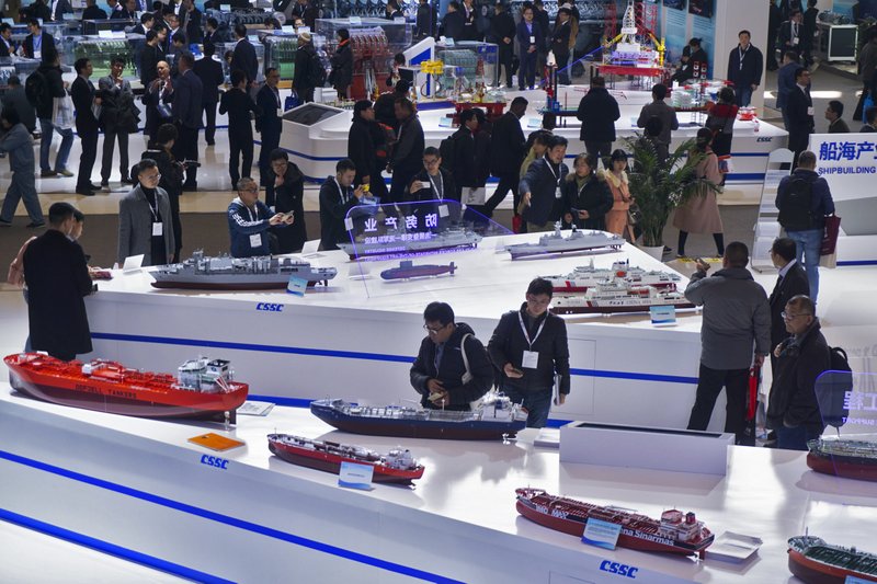 In this Tuesday, Dec. 3, 2019, photo, visitors look at the ship models exhibited by the China State Shipbuilding Corporation (CSSC) during the Marintec China exhibition in Shanghai, China. China's government promised Monday, Dec. 23, 2019, to open its oil, telecom and power markets wider to private competitors as the ruling Communist Party tries to shore up growth in the slowing, state-dominated economy. (Chinatopix via AP)