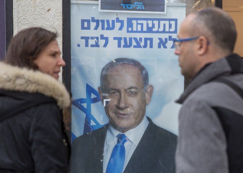 People look at a poster of Israel Prime Minister and governing Likud party leader Benjamin Netanyahu at a voting center in the northern Israeli city of Hadera on Thursday. Israel's governing Likud party was holding primaries on Thursday, in the first serious internal challenge to Israeli Prime Minister Benjamin Netanyahu in his more than a decade in power. - AP Photo/Ariel Schalit