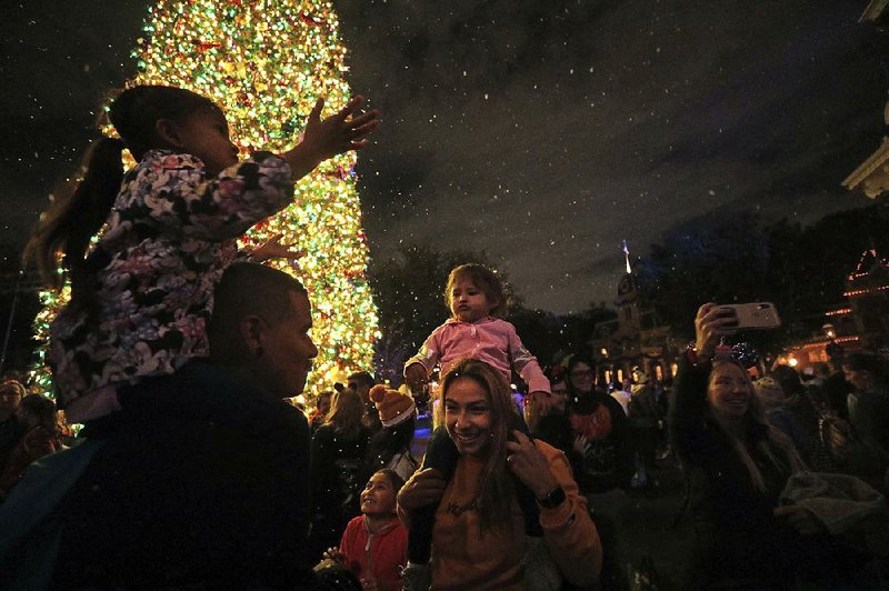 Tino Liquigan (left) and wife Raquel enjoy falling “snow” with their daughters Nov. 21 on Disneyland’s Main Street in Anaheim, Calif.  