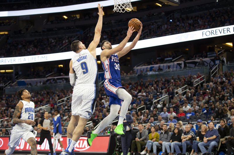Philadelphia 76ers guard Furkan Korkmaz (30) attempts to lay up the ball against Orlando Magic center Nikola Vucevic (9) during the first half of Friday's game in Orlando, Fla. - Photo by Willie J. Allen Jr. of The Associated Press