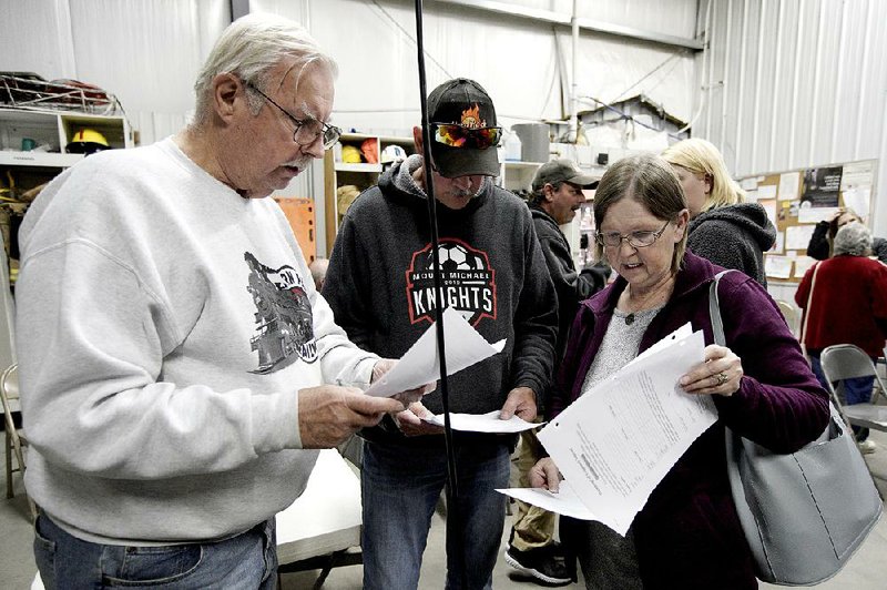 Richard Apking (left) and Debbie Johnson examine documents last fall after a town hall meeting in Winslow, Neb., during which relocating the village was discussed. More photos at arkansasonline.com/1229winslow/.