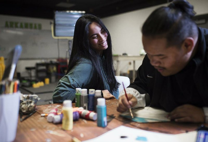 Marshallese artist Joyce Hitchfield works with Raygon Jacklick, 17, of Springdale on an art project earlier this month at The Station in Springdale.  