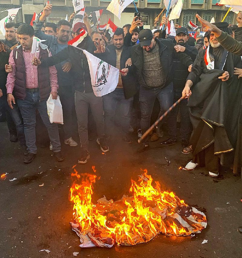 Protesters burn representations of an American flag Monday in Baghdad’s Tahrir Square during a protest against the U.S. strikes on the Kataeb Hezbollah militia. More photos at arkansasonline.com/1231strikes/. 