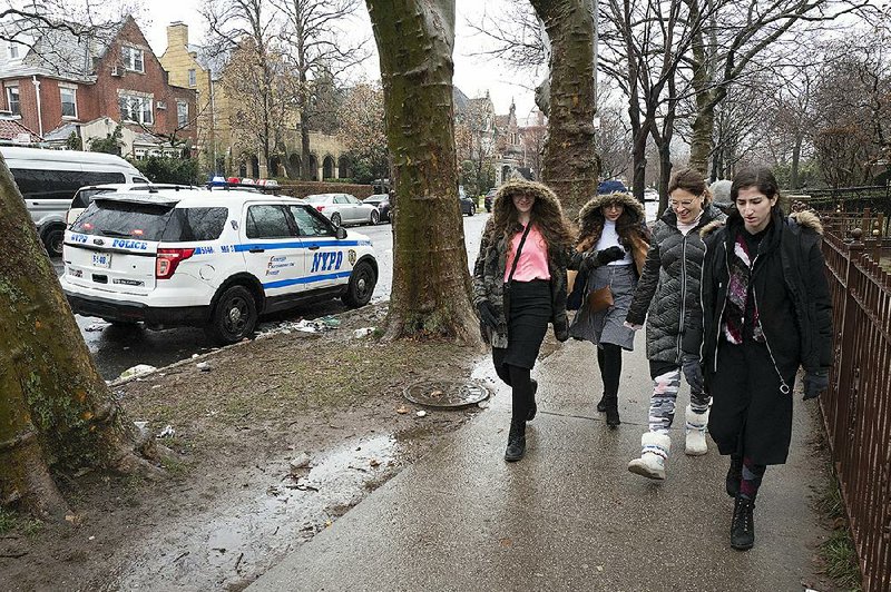 Jewish girls walk past a New York City police car stationed Monday in the Crown Heights neighborhood of Brooklyn. Police have increased patrols after a series of violent attacks targeting Jewish communities in the region.  