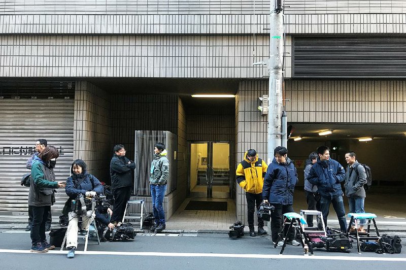 Journalists linger Tuesday at the back entrance of a Tokyo building that houses the offices of Junichiro Hironaka, a lawyer for Nissan’s former Chairman Carlos Ghosn.
(AP/Richard Colombo)