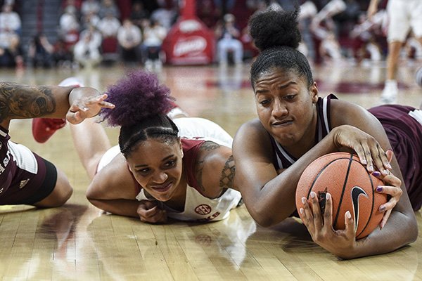 Arkansas forward Kiara Williams (left) and Texas A&M center Ciera Johnson (right) dive for a loose ball during a game Thursday, Jan. 2, 2020, in Fayetteville.