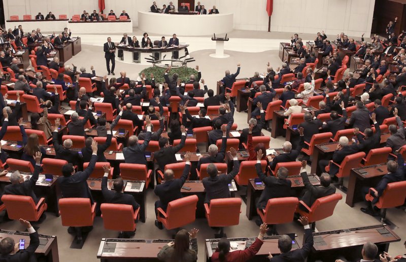 Members of Turkey's parliament vote to send Turkish troops to Libya to help the U.N.-supported government in Tripoli battle forces loyal to a rival administration in eastern Libya that is seeking to capture the capital, in Ankara, Turkey, Thursday, Jan. 2, 2020. The Turkish lawmakers approved a motion at the emergency session and granted a one-year mandate for the deployment, despite concerns that Turkish forces could aggravate Libya's conflict further and destabilize the region.(AP Photo/Burhan Ozbilici)

