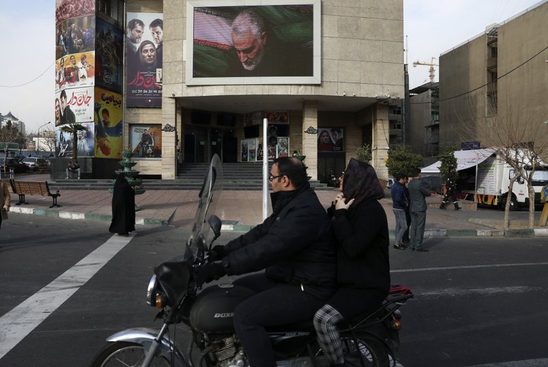 People make their way on the street while a screen on the wall of a cinema shows a portrait of Iranian Revolutionary Guard Gen. Qassem Soleimani, who was killed in the U.S. airstrike in Iraq that killed, in Tehran, Iran, Jan. 3, 2020. Iran has vowed "harsh retaliation" for the U.S. airstrike near Baghdad's airport that killed Tehran's top general and the architect of its interventions across the Middle East, as tensions soared in the wake of the targeted killing. (AP Photo/Vahid Salemi)

