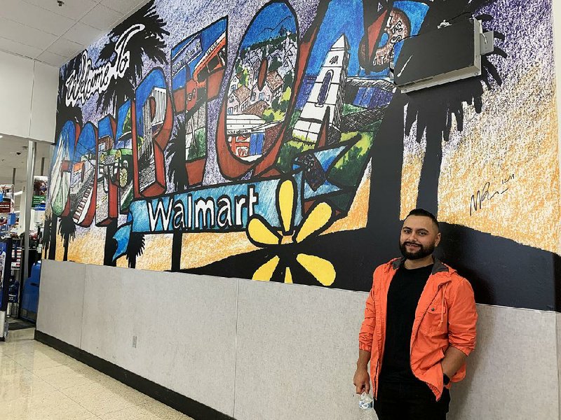Michael Rangel stands in a Compton, Calif., Walmart Supercenter next to a mural he designed.
(Courtesy of Walmart)