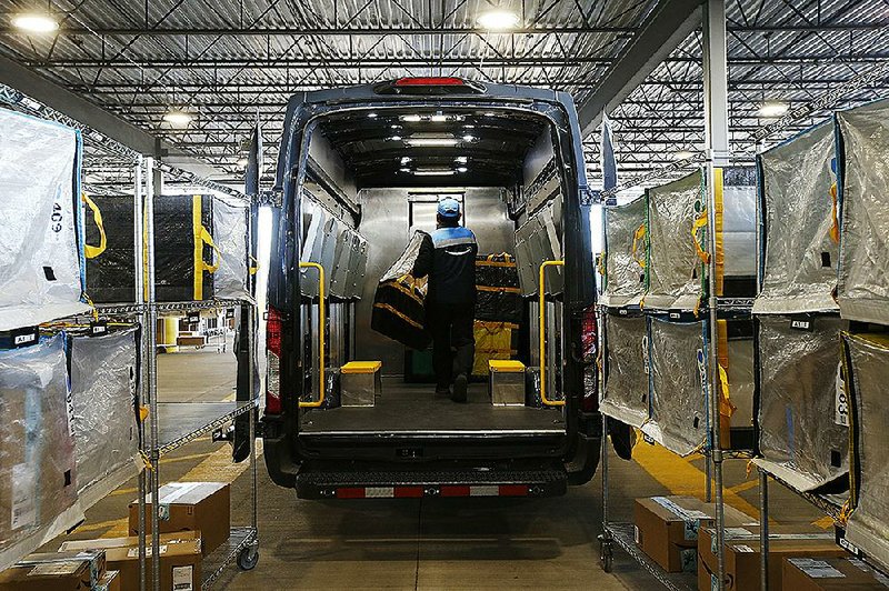 A delivery driver stows containers in his truck delivered by Amazon robots at an Amazon warehouse in Goodyear, Ariz. 