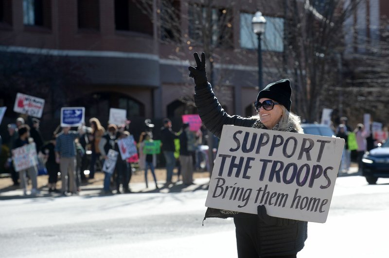 NWA Democrat-Gazette/ANDY SHUPE Susie Cox of Fayetteville gestures to passing cars Saturday while holding a sign along College Avenue at Dickson Street during a protest of the threat of war with Iran organized by the Omni Center for Peace, Justice &amp; Ecology and the Arkansas Nonviolence Alliance in front of the Washington County Courthouse in Fayetteville. The protest comes after the U.S. killing of Qassem Soleimani, Iran's top military leader. Go to nwaonline.com/200105Daily/ for today's photo gallery.