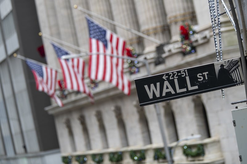 FILE - In this Friday, Jan. 3, 2020 file photo, the Wall St. street sign is framed by American flags flying outside the New York Stock Exchange, in New York. Global stock markets are falling Monday, Jan. 6 while oil and gold prices are rising as tensions escalate between the U.S. and Iran. Markets have been roiled since Friday after the U.S. killed Iran's top general. (AP Photo/Mary Altaffer, File)