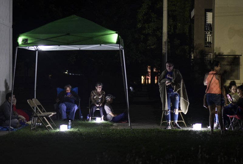 Neighbors remain outdoors using camping tents and portable lights for fear of possible aftershocks on their first night after a 6.4-magnitude earthquake struck in Guanica, Puerto Rico, Tuesday, Jan. 7, 2020. The quake was followed by a series of strong aftershocks, part of a 10-day series of temblors spawned by the grinding of tectonic plates along three faults beneath southern Puerto Rico. (AP Photo/Carlos Giusti)

