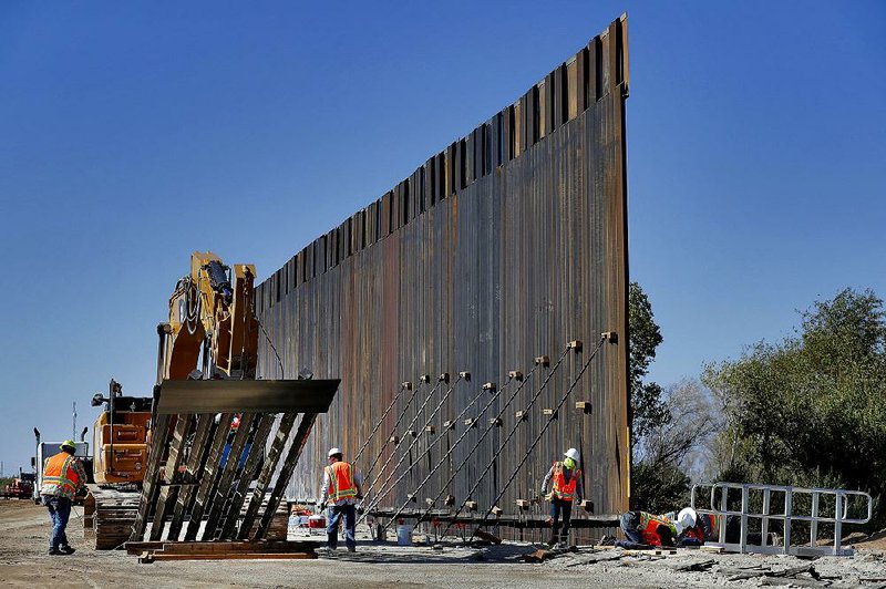 Government contractors erect a section of Pentagon-funded border wall along the Colorado River in Yuma, Ariz., in September. The White House says construction of the U.S.-Mexico border wall will move forward after a federal appeals court ruling that frees up construction money.  
