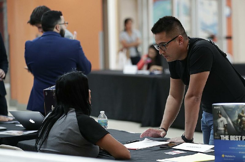 A job hunter (right) talks with a GameStop representative at a Miami career fair in October. The government reported Friday that an average of about 175,000 jobs per month were added in 2019, compared with about 223,250 per month in 2018.  