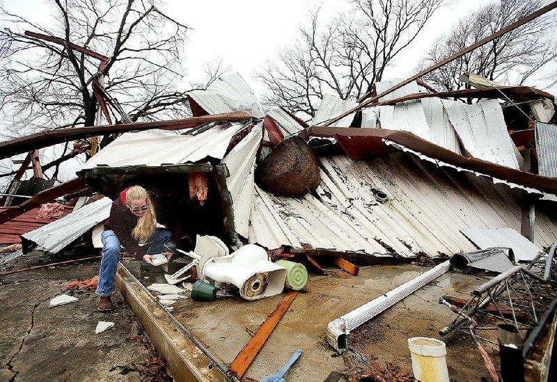 Scarlett Faulk of Austin salvages a Bible belonging to one of her brothers as she searches for items in a destroyed building on her family’s land Saturday in southern Lonoke County. There were no injuries reported from the storm. More photos at www.arkansasonline.com/112storms/.  