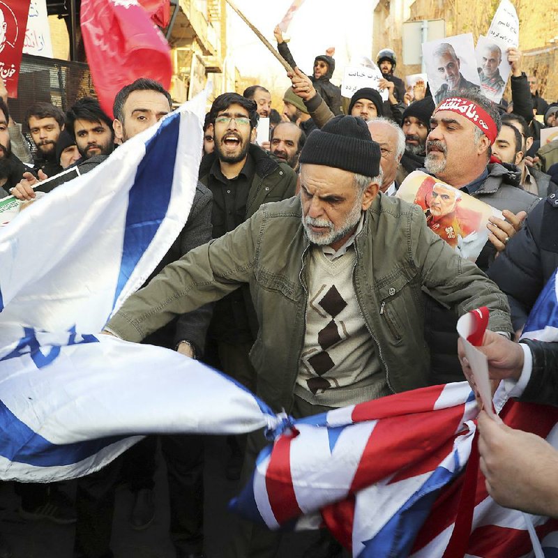 Protesters in front of the British Embassy in Tehran, Iran, prepare Sunday to burn representations of the Israeli and British flags. The demonstrators called for the closure of the embassy and the expulsion of British Ambassador Rob Macaire after he attended a vigil that turned into an anti-government protest. More photos at arkansasonline.com/113tehran/. 