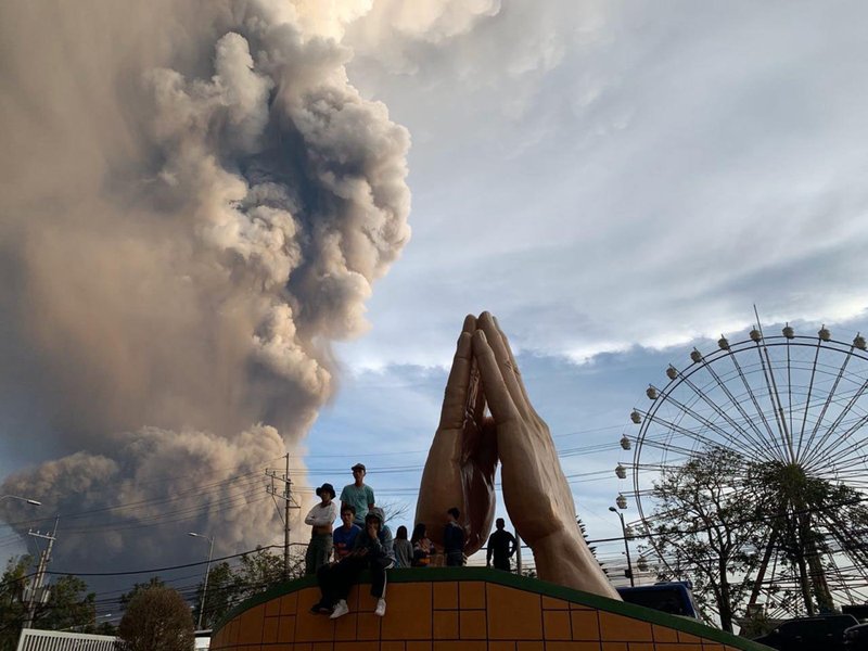 People watch as the Taal volcano spews ash and smoke during an eruption in Tagaytay, Cavite province south of Manila, Philippines on Sunday. A tiny volcano near the Philippine capital that draws many tourists for its picturesque setting in a lake belched steam, ash and rocks in a huge plume Sunday, prompting thousands of residents to flee and officials to temporarily suspend flights. - AP Photo/Bullit Marquez