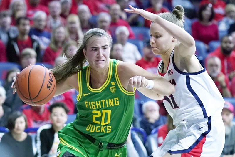 Oregon guard Sabrina Ionescu (20) drives around Arizona guard Mara Mote during the first half of Sunday's game in Tucson, Ariz. - Photo by Rick Scuteri of The Associated Press story.lead_photo.caption