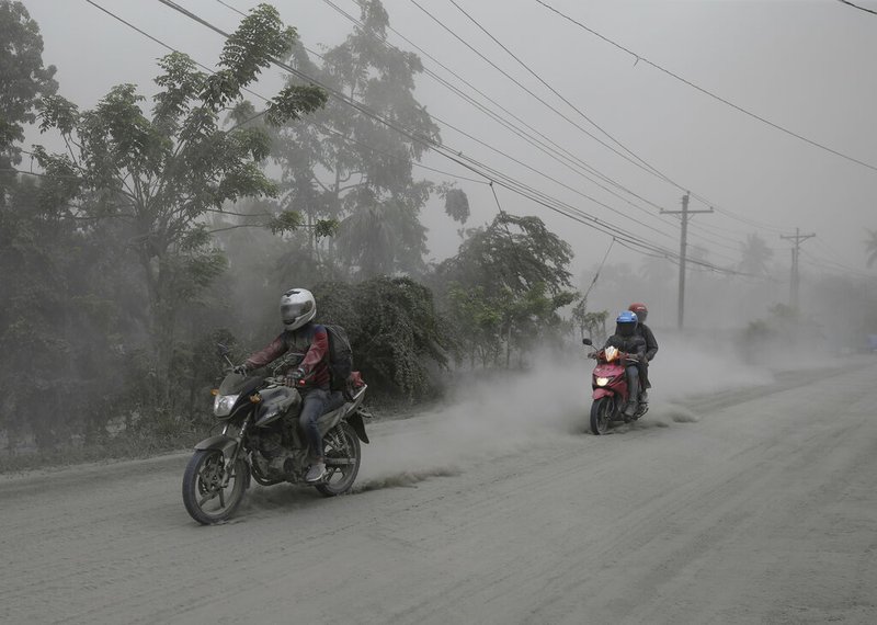Motorcycles ride along an ash covered road as they evacuate to safer grounds as Taal volcano in Lemery, Batangas, southern Philippines on Monday, Jan. 13, 2020. Red-hot lava gushed out of a volcano near the Philippine capital on Monday, as thousands of people fled the area through heavy ash. Experts warned that the eruption could get worse and plans were being made to evacuate hundreds of thousands. (AP Photo/Aaron Favila) story.lead_photo.caption