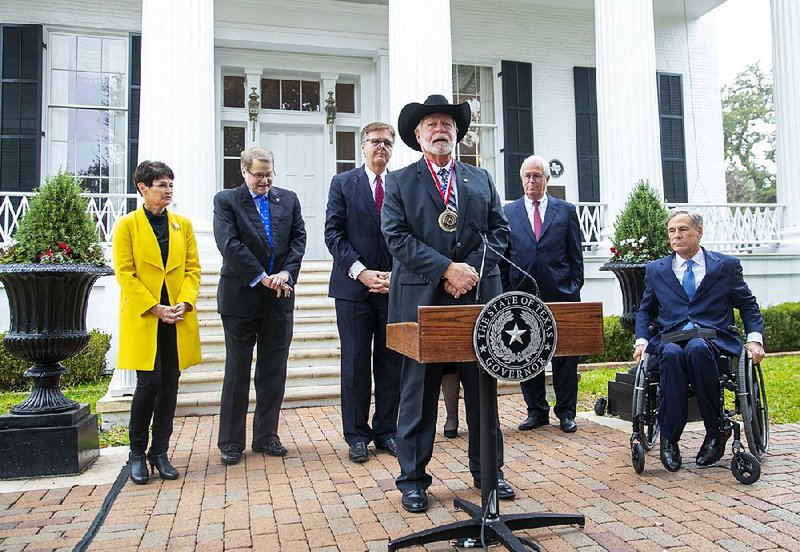 Jack Wilson (front) receives the medal on Monday during a ceremony with Gov. Greg Abbott (right) in Austin, Texas.  