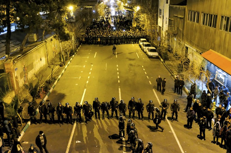 In this photograph taken Saturday, Jan. 11, 2020, Iranian police officers take position while protesters gather in front of Amir Kabir University in Tehran, Iran, to remember victims of a Ukrainian airplane shot down by an Iranian missile. Online videos purported to show Monday, Jan. 13, 2020, that Iranian security forces fired both live ammunition and tear gas to disperse demonstrators protesting against the Islamic Republic's initial denial that it shot down a Ukrainian jetliner. (AP Photo)