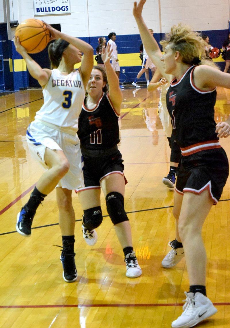 Westside Eagle Observer/MIKE ECKELS Finding the path to the basket blocked by a pair of Lady Highlander defenders, Destiny Mejia (3) passes the ball to a teammate standing near the left-wing during the Decatur-Eureka Springs girls conference contest in Decatur Jan. 7.