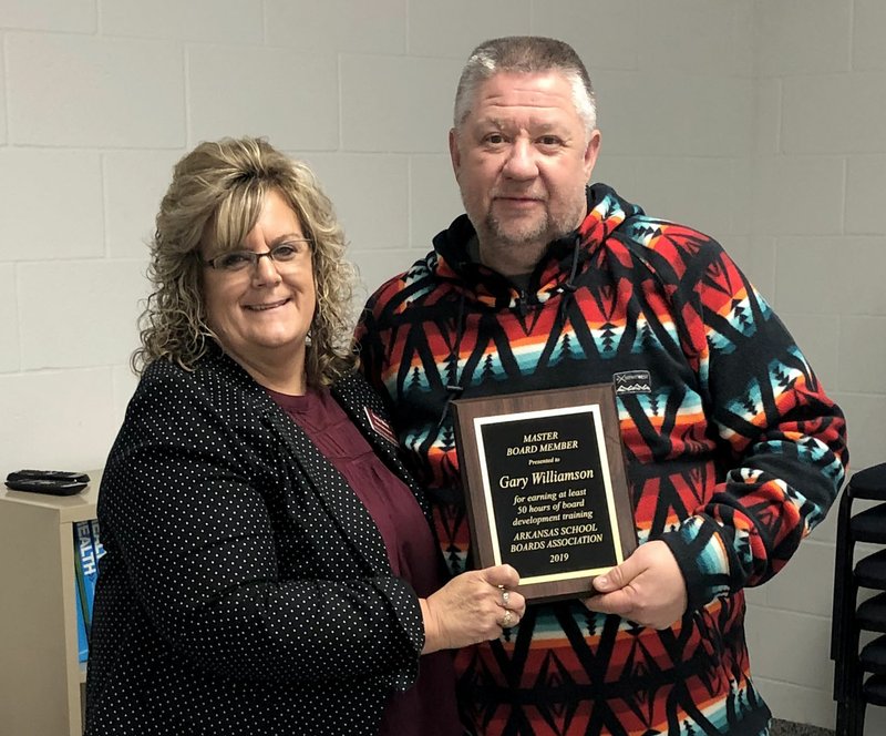 Westside Eagle Observer/RANDY MOLL David Williamson (right), president of the Gentry School Board, was honored Monday with a plaque, presented by district superintendent Terrie Metz, for being a master board member, which requires completing a minimum of 50 hours of board training.