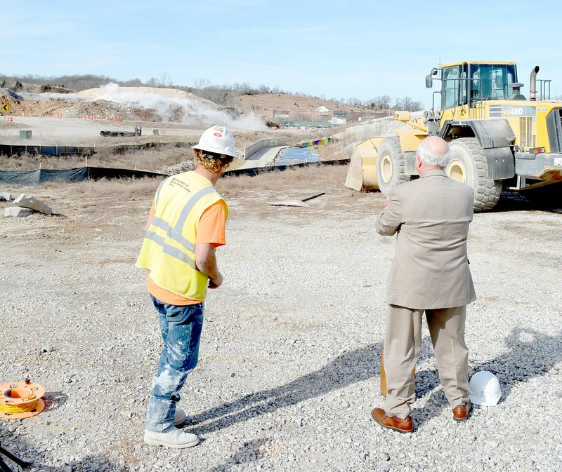 Keith Bryant/The Weekly Vista Zack Brisco, blaster with Explosive Contractors, Inc., watches the now-flattened hillside collapse with Mayor Peter Christie, who just pushed a plunger to detonate a series of charges that turned part of the hill into a pile of dirt and rocks.