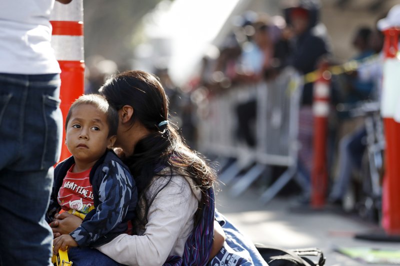 FILE - In this July 16, 2019, file photo, a woman sits with her sons as they wait to apply for asylum in the United States along the border in Tijuana, Mexico. A federal judge rules that the Trump administration is operating within its authority when separating families stopped at the Mexican border, rejecting arguments that it was quietly returning to widespread practices that drew international condemnation. (AP Photo/Gregory Bull, File)