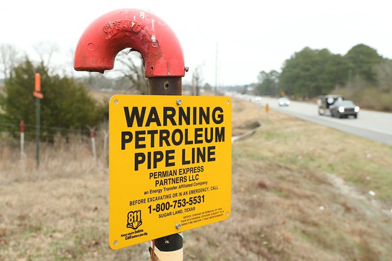 The Sentinel-Record/Richard Rasmussen TESTING UNDERWAY: Motorists drive past a warning sign Tuesday for the Permian Express Pipeline in the 6400 block of Albert Pike Road. The pipeline's owner began testing the inactive line this week.