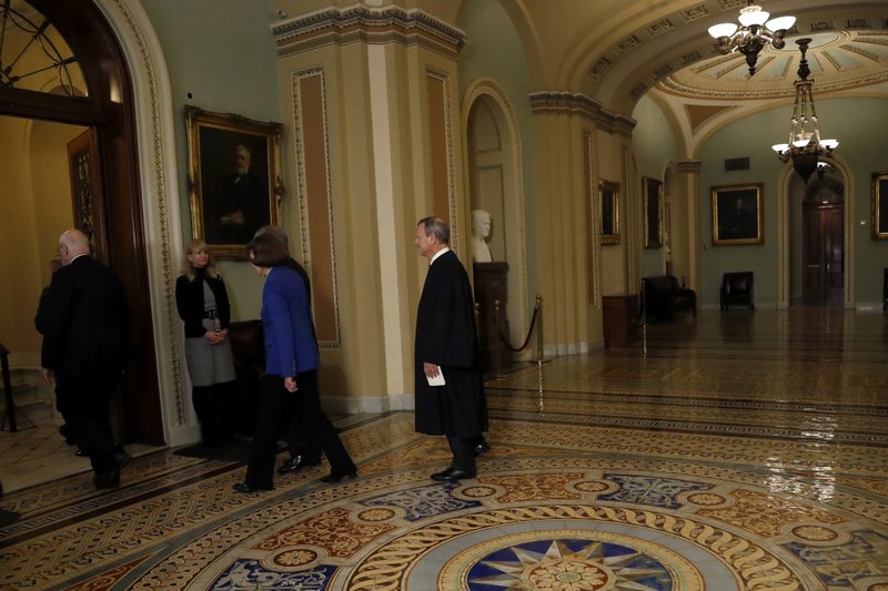 Chief Justice of the United States John Roberts, right, walks to the Senate chamber at the Capitol in Washington, Thursday, Jan. 16, 2020. (AP Photo/Julio Cortez)