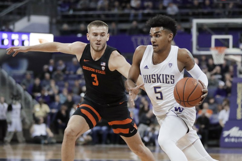 Washington guard Jamal Bey (5) drives around Oregon State forward Tres Tinkle (3) during the first half of Thursday's game in Seattle. - Photo by Ted S. Warren of The Associated Press