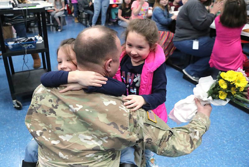 U.S. Army Sgt. Michael Garrett, of Jessieville, reunites with his daughters Rayleigh, 7, left, and Sofia, 5, right, at Jessieville Elementary School Friday. Garrett had not seen them for one year while he was stationed in South Korea. - Photo by Richard Rasmussen of The Sentinel-Record