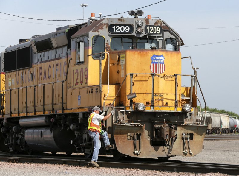 In this July 20, 2017, file photo, a Union Pacific employee climbs on board a locomotive in a rail yard in Council Bluffs, Iowa. This year's scheduled completion of a $15 billion automatic railroad braking system will bolster the industry's argument for eliminating one of the two crew members in most locomotives. But labor groups argue that single-person crews would make trains more accident prone. - AP Photo/Nati Harnik